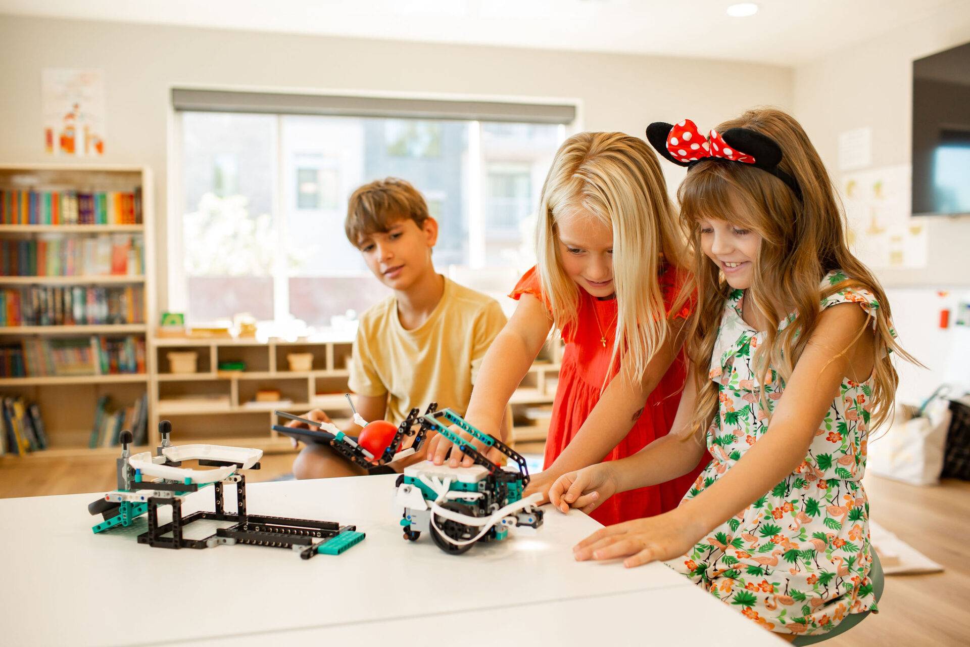 A group of students, one boy and two girls, playing with lego robotics at Acton Academy St. George