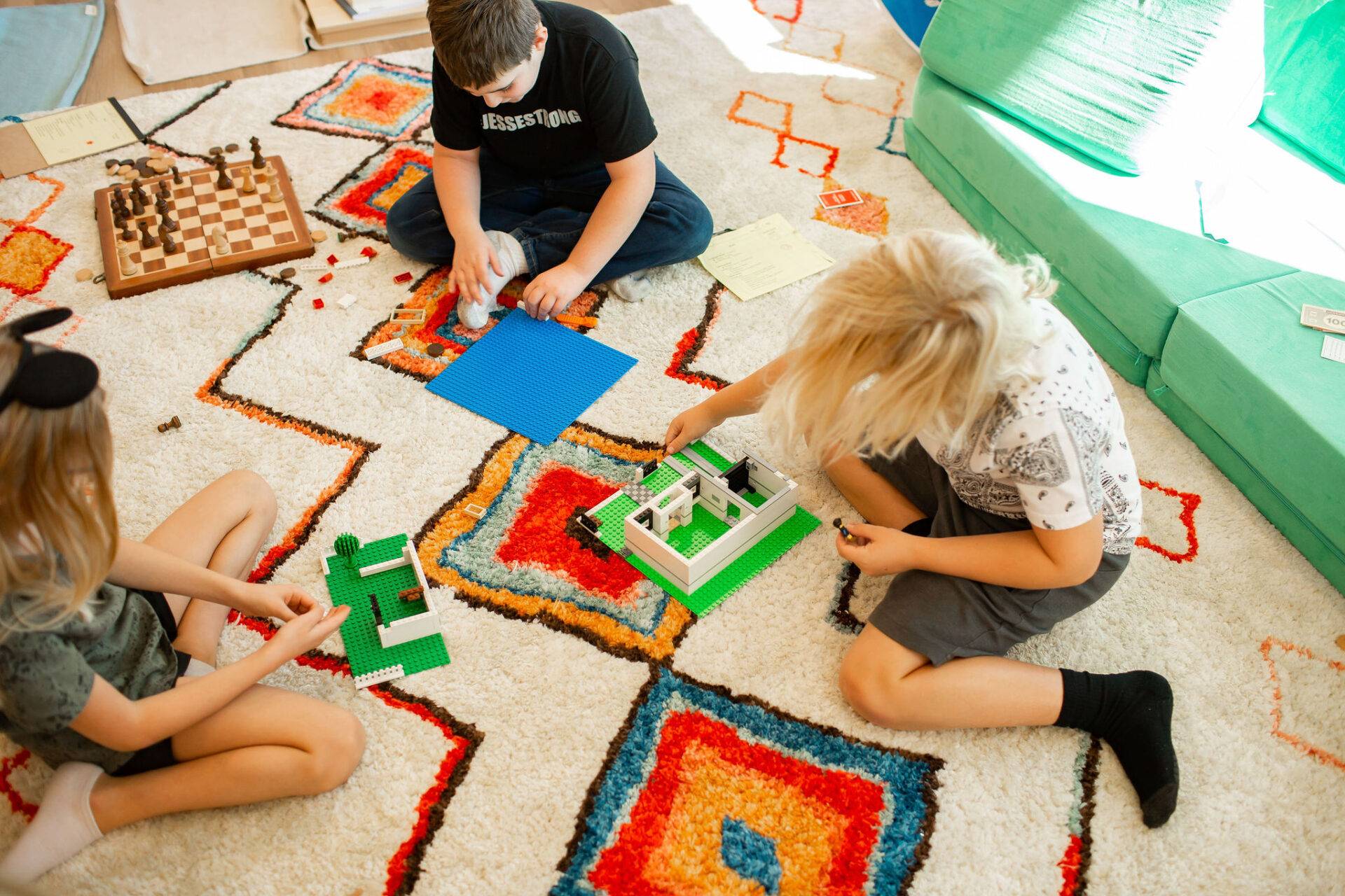 a group of students at Acton Academy St. George building legos and play chess on the floor of their classroom